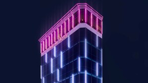 A multi-story hotel with a modern glass facade and neon signage. - Thai Ha Hotel (Bai Chay)
