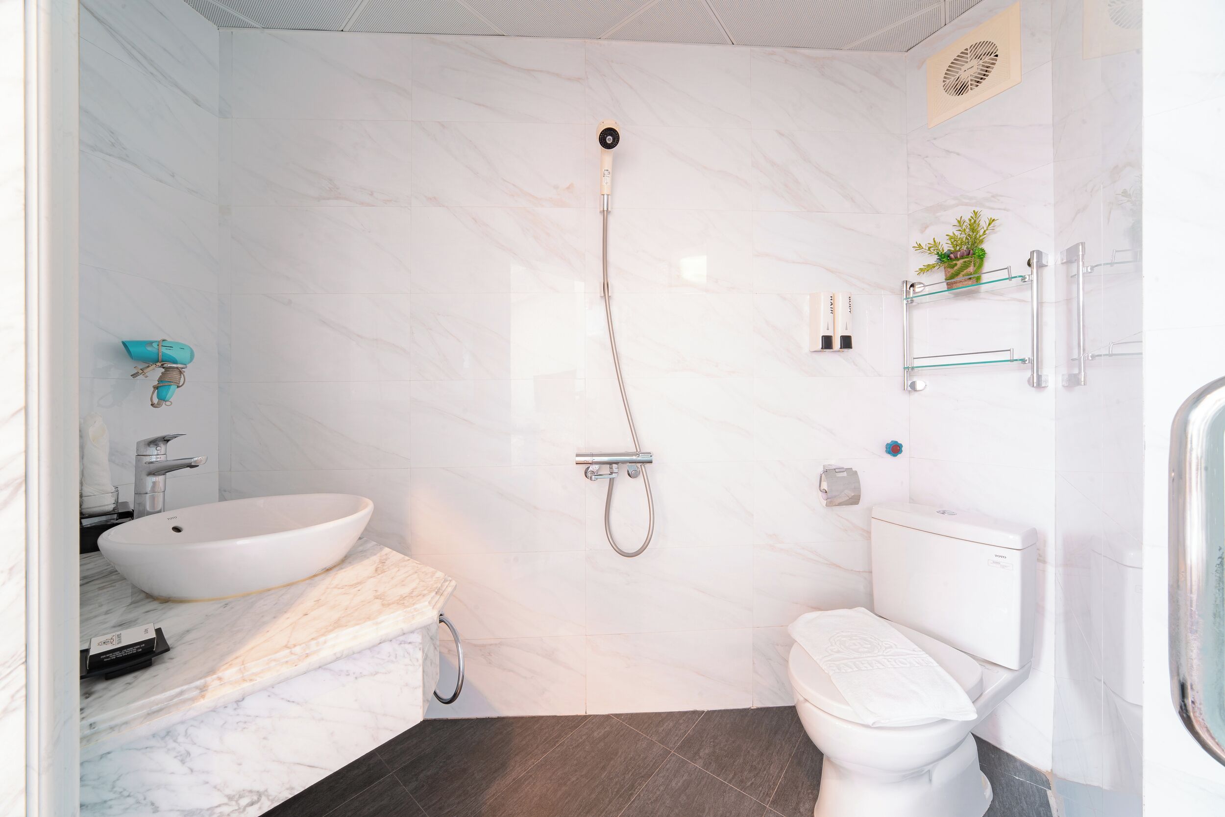 A modern bathroom with a white sink, a toilet, and a shower.