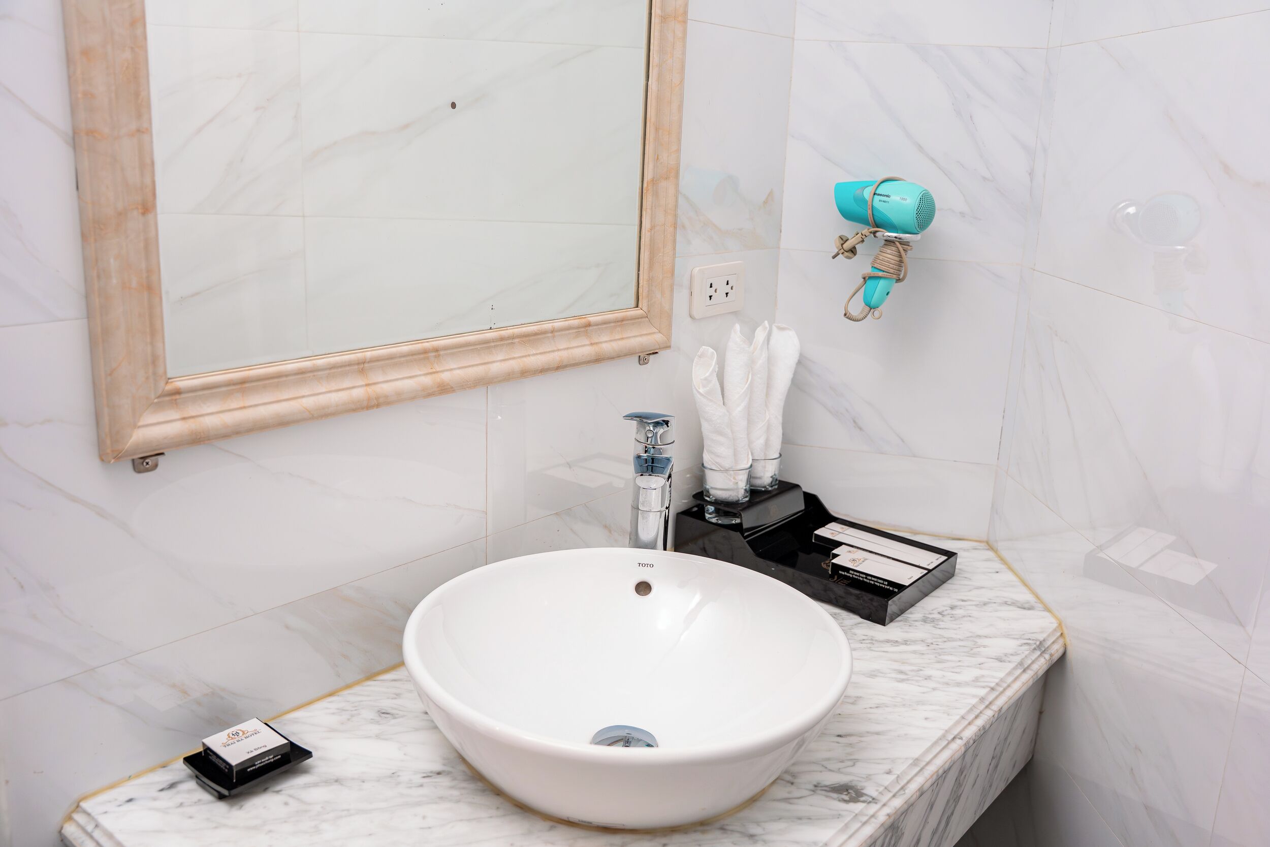 A bathroom with a white marble sink, a mirror, a towel rack, and a hairdryer.
