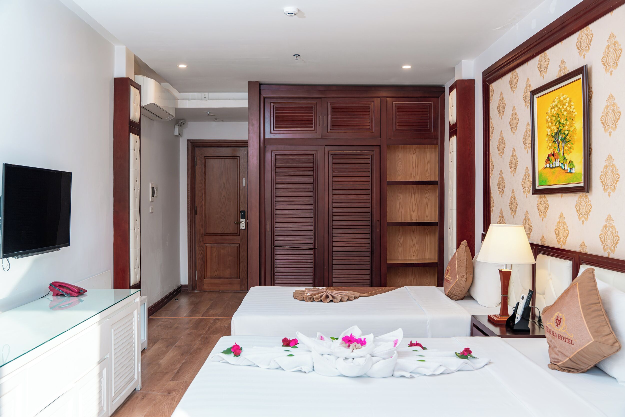 A hotel room with two beds, a TV, a desk, and a wardrobe.