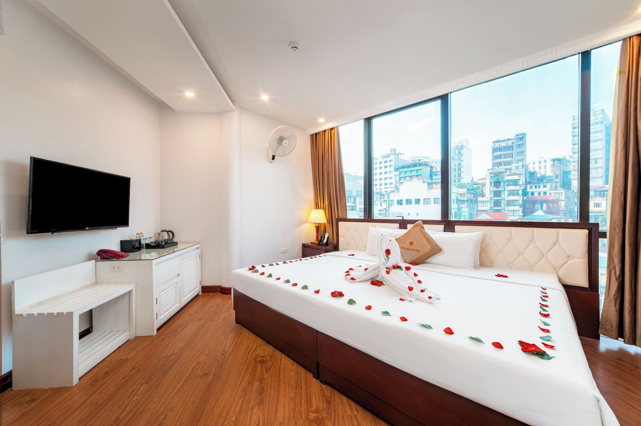 A hotel room with a bed, a TV, a desk, and a city view.