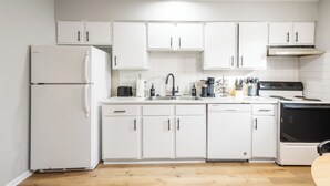 Une cuisine moderne avec des meubles blancs, un réfrigérateur, une cuisinière et un évier.