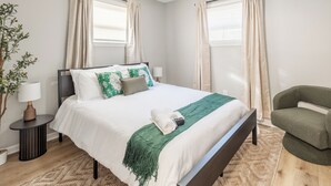 Une chambre bien rangée, avec un lit, des tables de chevet, une chaise et un ventilateur de plafond.