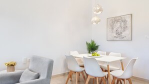 Ein moderner Essbereich mit einem weißen Tisch, grauen Stühlen und einem grauen Sofa.