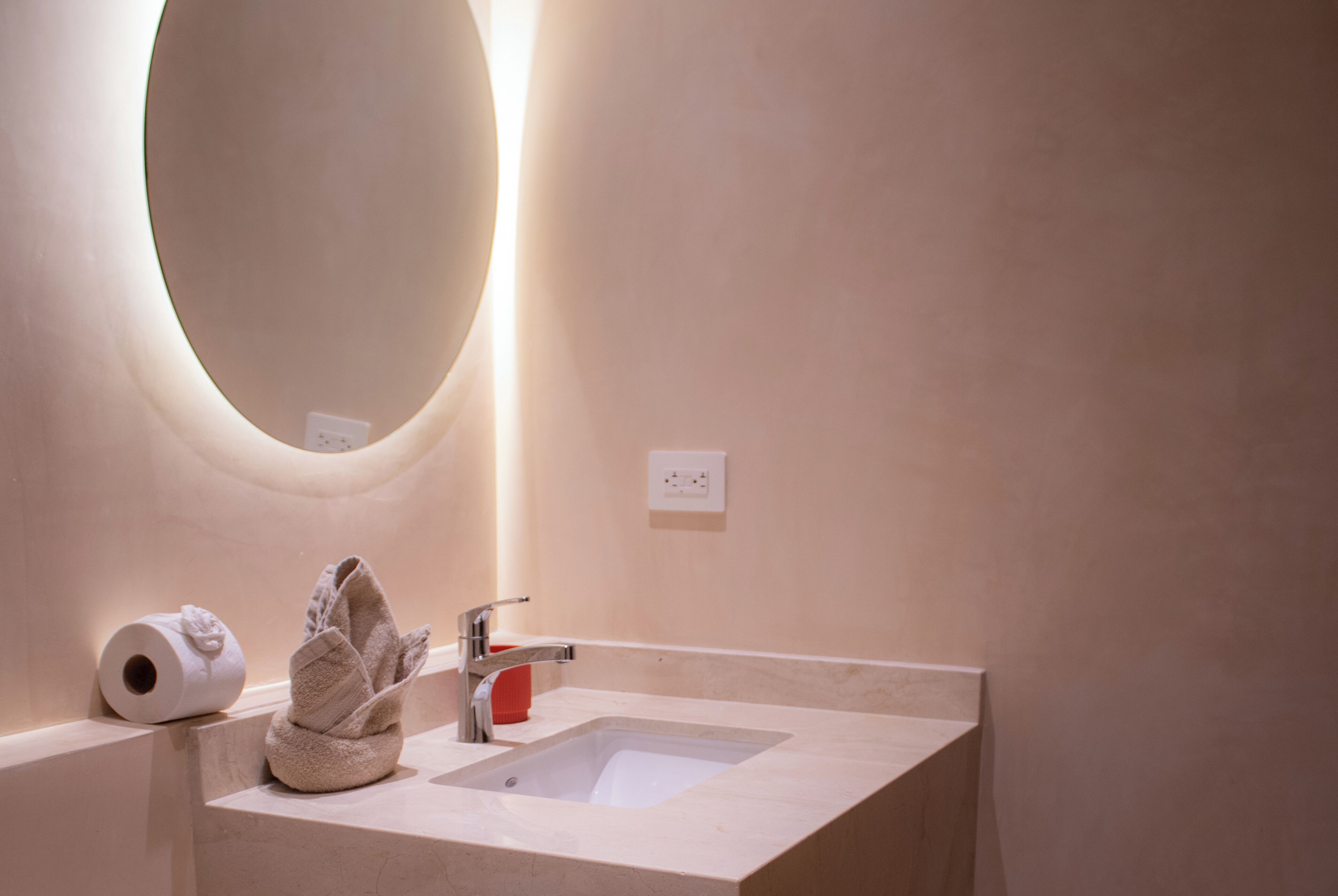 A bathroom with a sink, a towel, and a toilet paper roll.