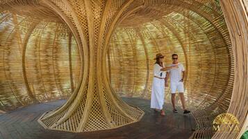 Una pareja de pie dentro de una estructura circular tejida con suelo de madera.