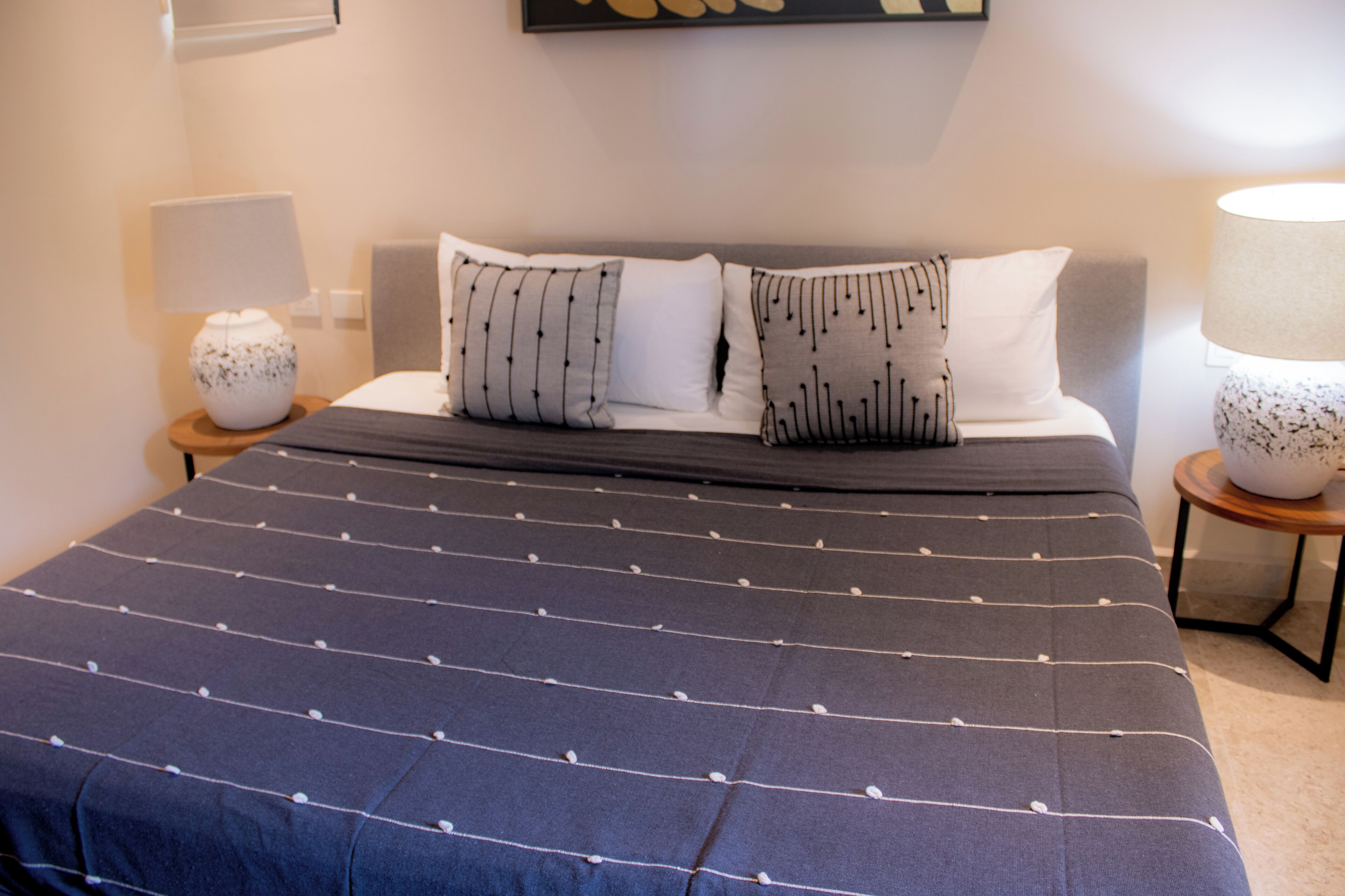 A neatly made bed with a striped bedspread and two pillows with a striped pattern.
