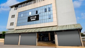 A modern hotel building with a large glass facade, a sign reading 'HOTELO,' and a metal roof. - Super Hotel O Pachgaon (Kolhapur)