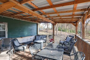 Una terraza al aire libre techada con mobiliario metálico, una mesa y un sofá.