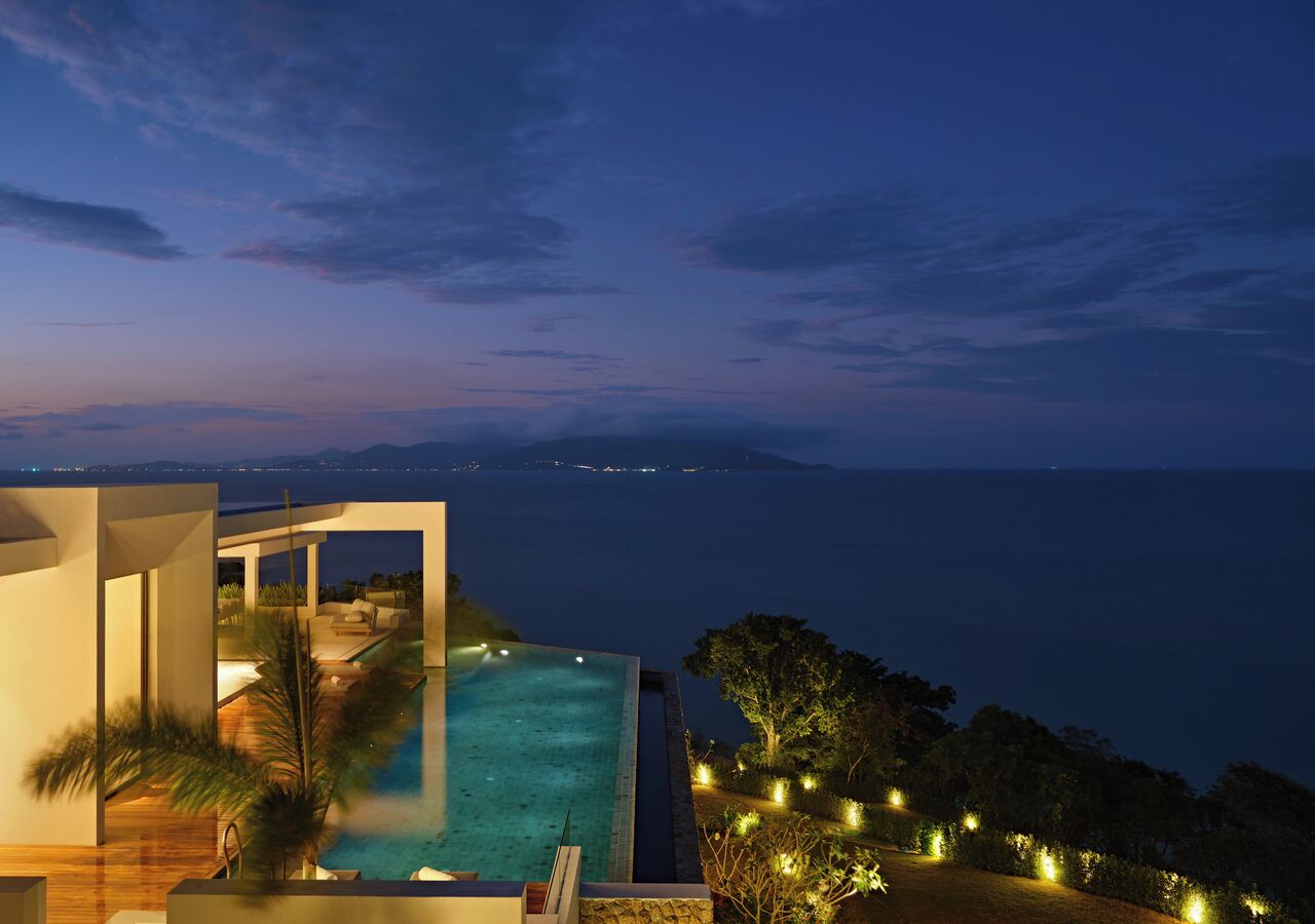 A modern infinity pool with a view of the sea at dusk.