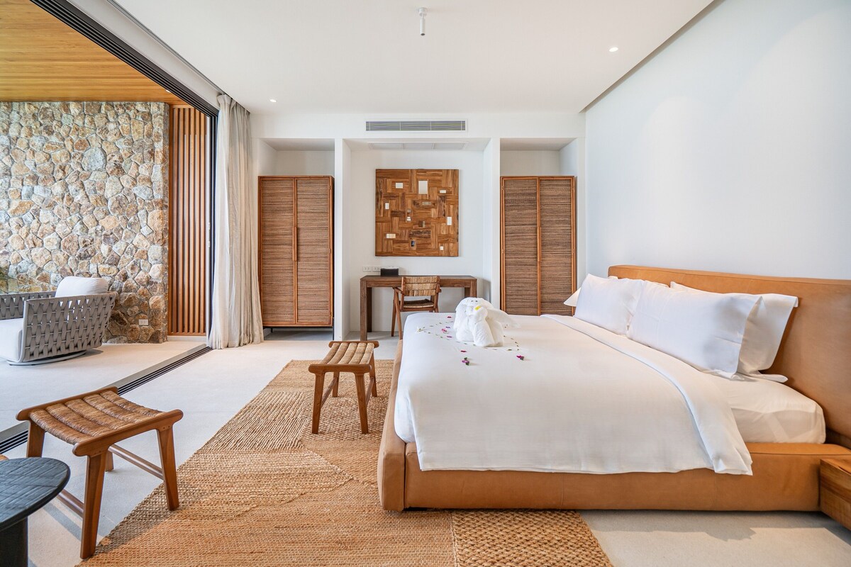 A modern hotel room with a large bed, a desk, and a seating area.