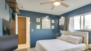 Une chambre à coucher avec un lit, un ventilateur de plafond, une fenêtre et une porte.
