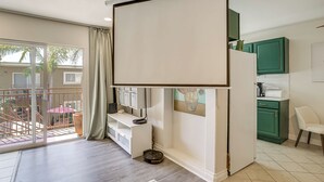 Un appartement moderne doté d’un balcon, d’une cuisine avec des meubles verts et d’un meuble de rangement blanc pour les appareils électroniques.