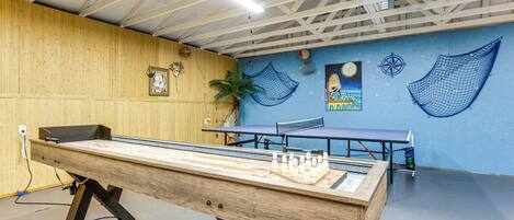 Una mesa de ping pong en una habitación con pared azul, paneles de madera y techo con vigas a la vista.