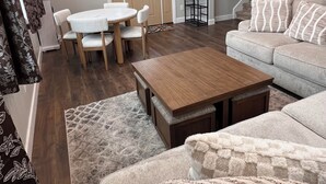 Ein modernes Wohnzimmer mit einer Couch, einem Couchtisch und einem Esstisch mit Stühlen. Eine Treppe führt zu einer weiteren Ebene.