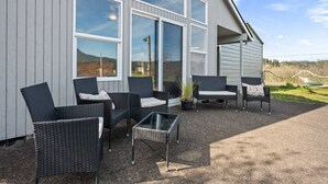 Ein Gebäude mit großen Fenstern, Gartenmöbeln aus Rattan und einem Glastisch.