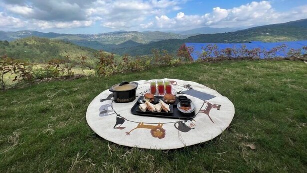 Ein Picknick auf einem grasbewachsenen Hügel mit herrlichem Blick auf Berge und einen See.