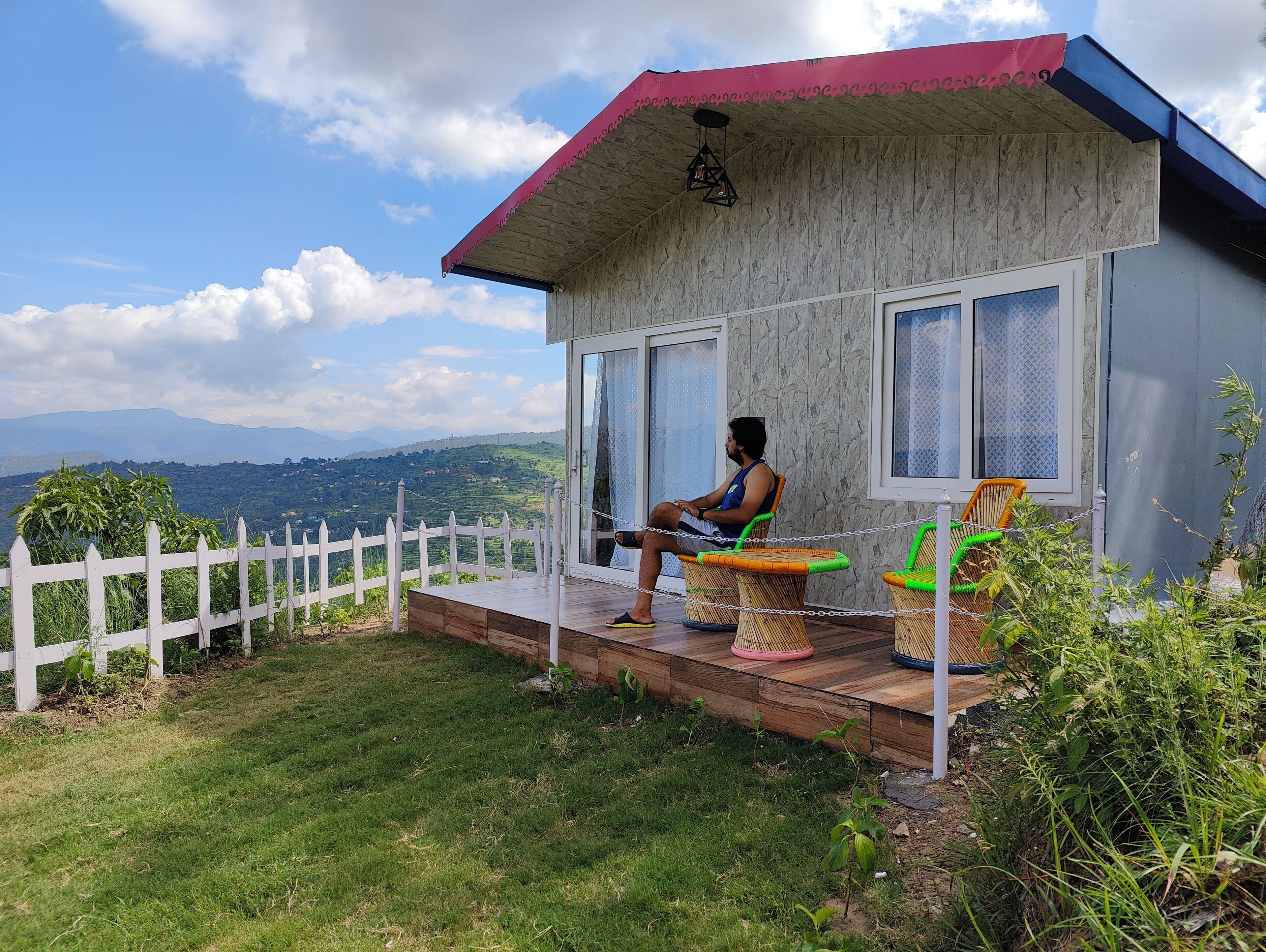 A person sitting on a chair outside a building with a view of the mountains.