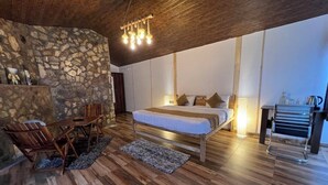 Ein Schlafzimmer mit Steinswand, Holzboden, einem Bett, einem Schreibtisch und einem Stuhl.