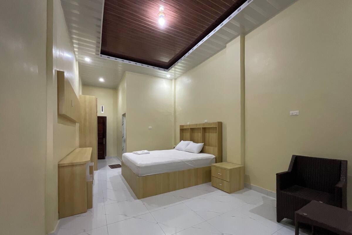 A modern bedroom with a bed, bedside tables, a chair, and a walk-in closet.