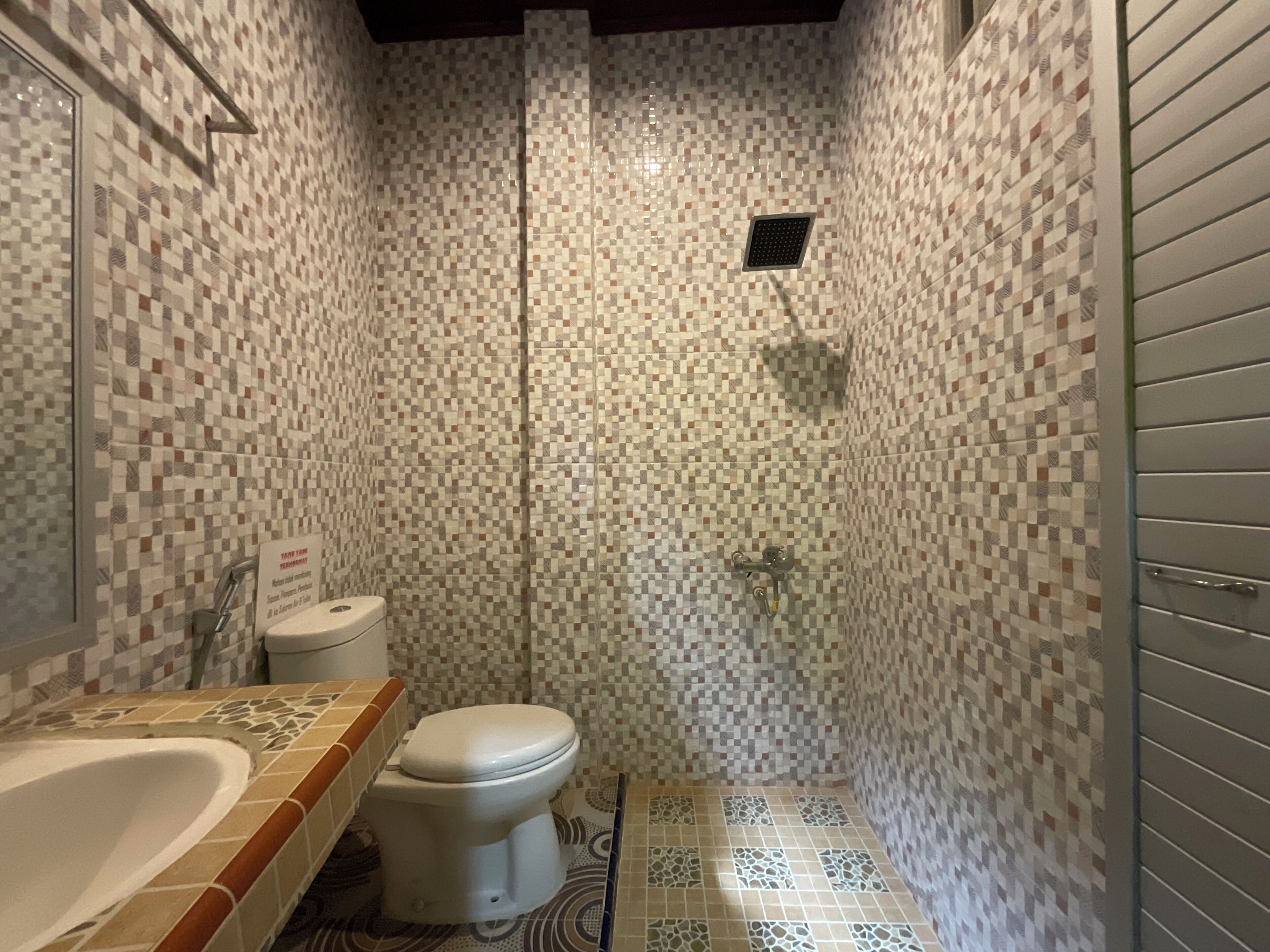 A bathroom with a mosaic tile wall, a toilet, a shower, and a bathtub.