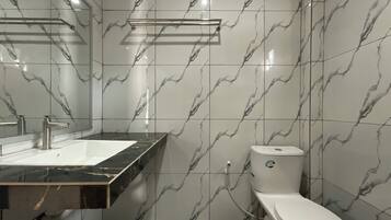 A bathroom with a white toilet, a sink with a black countertop, and marble-patterned walls.