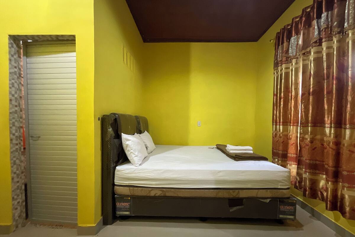 A room with a bed, a door, and a curtain.