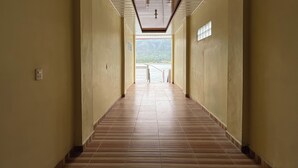 Un lungo corridoio stretto con pavimento piastrellato e soffitto illuminato da un lampadario centrale.