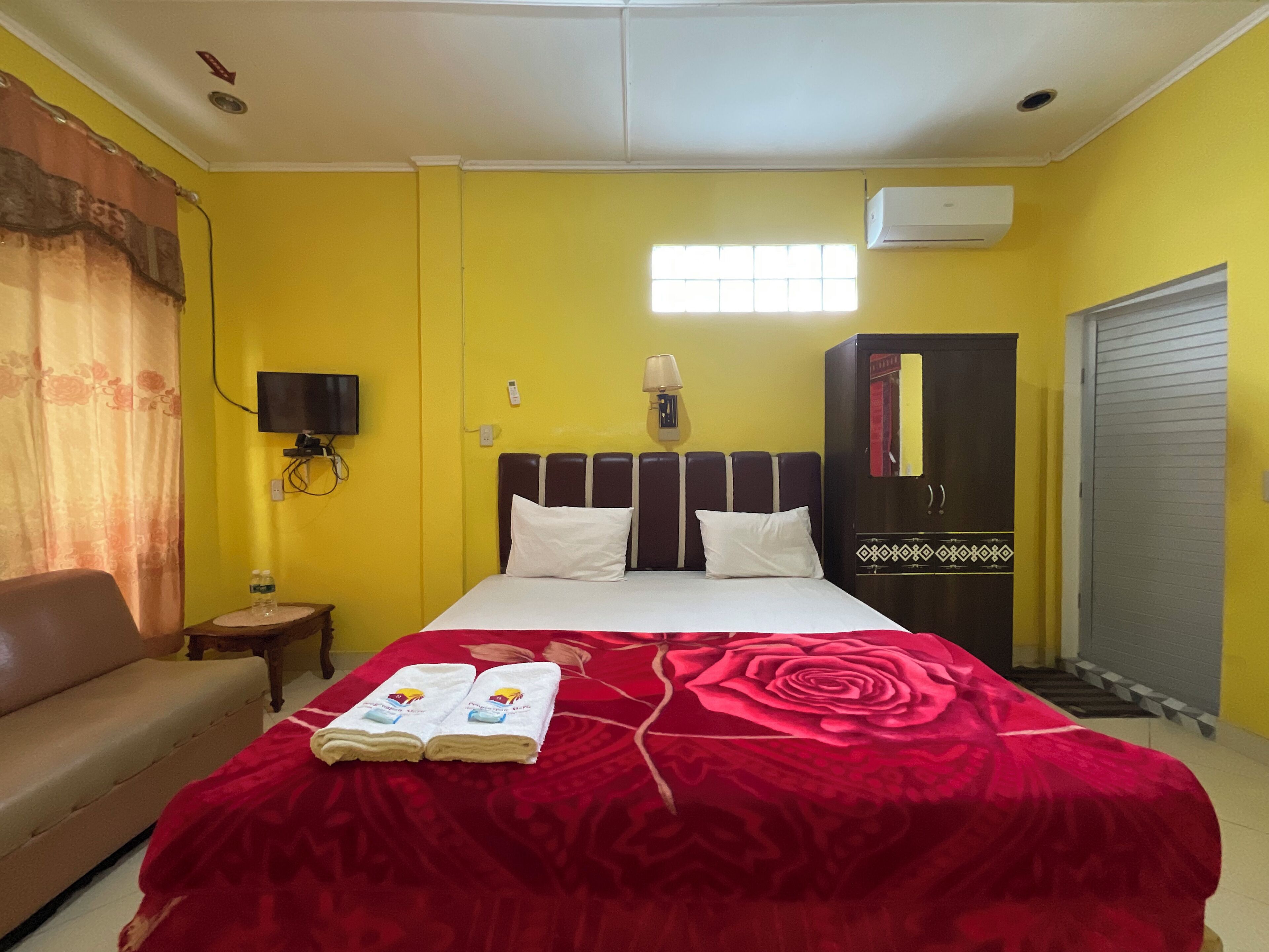 A hotel room with a bed, a TV, a wardrobe, and a window.