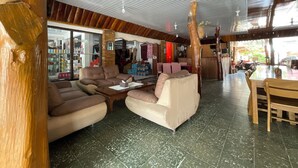 Un'ampia zona giorno con soffitto alto, dettagli in legno e un'area pranzo con tavolo e sedie.