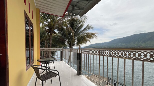 Un balcone con vista su un lago e montagne, con un tavolo e sedie.
