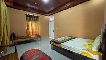 Quarto com cama, cadeira de madeira, mesa pequena e janela com cortinas.