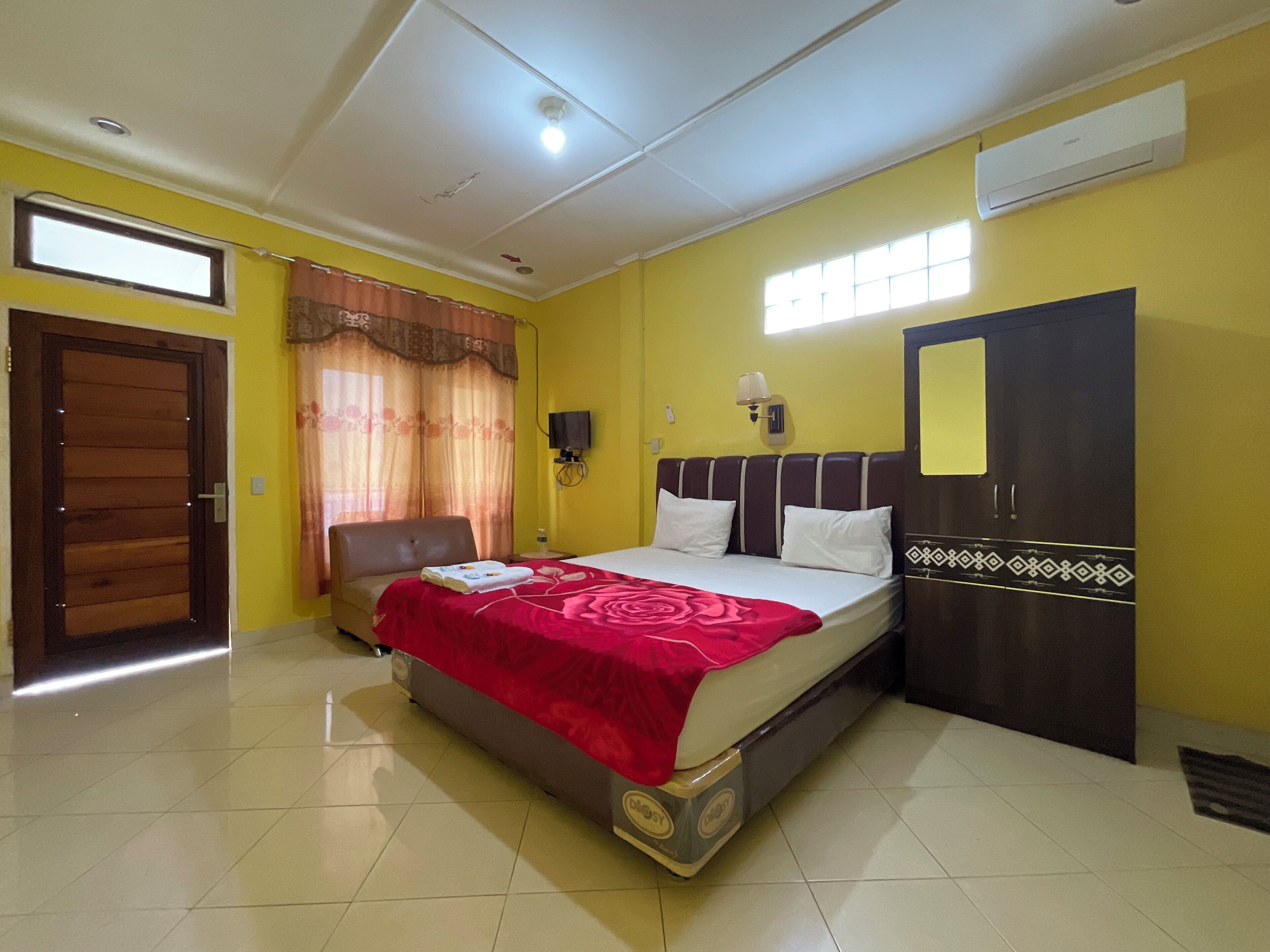 Une chambre à coucher comprenant un lit, une chaise, une armoire, une fenêtre et un appareil de climatisation.