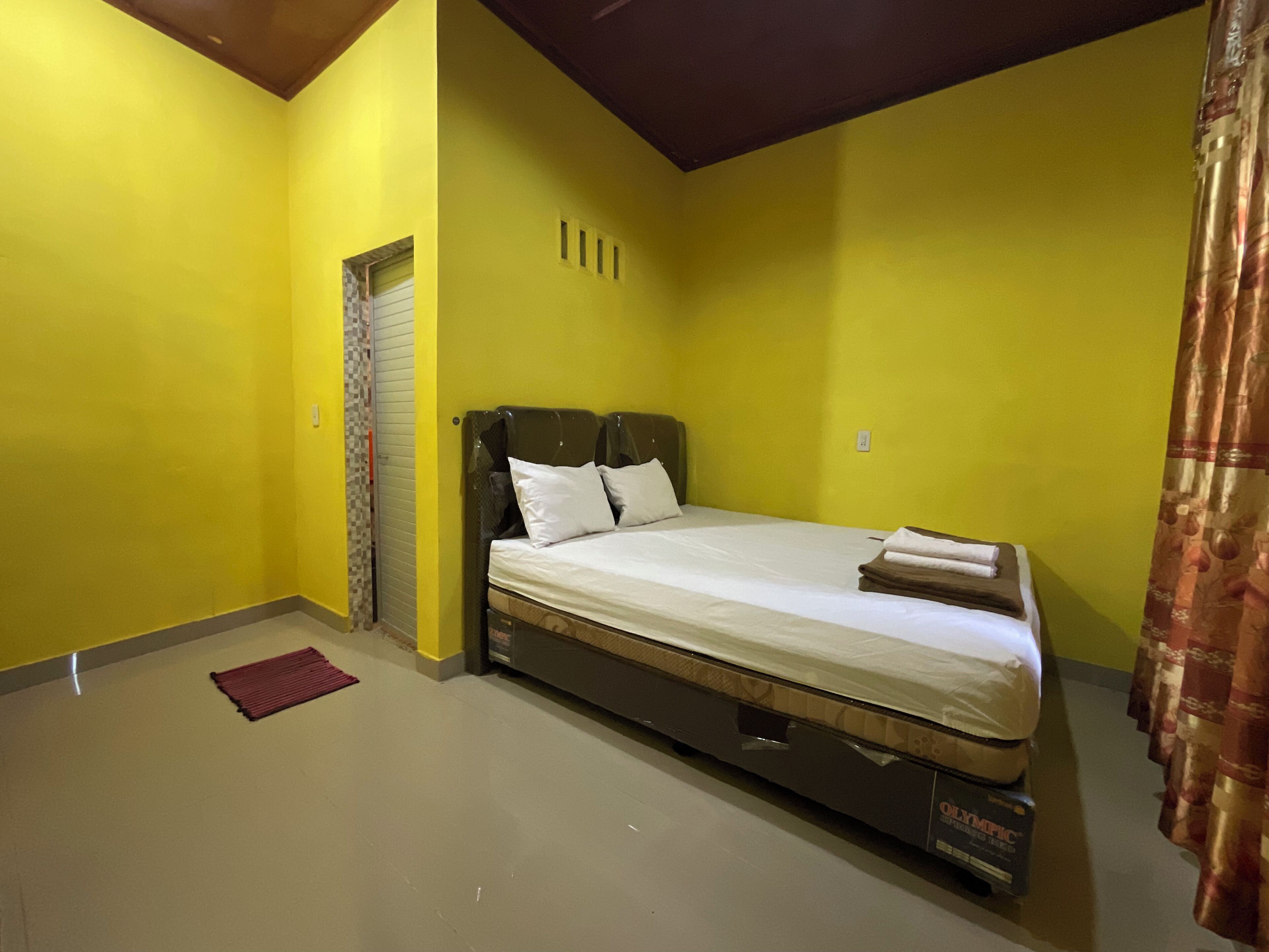 A single bed in a room with yellow walls and a brown ceiling.