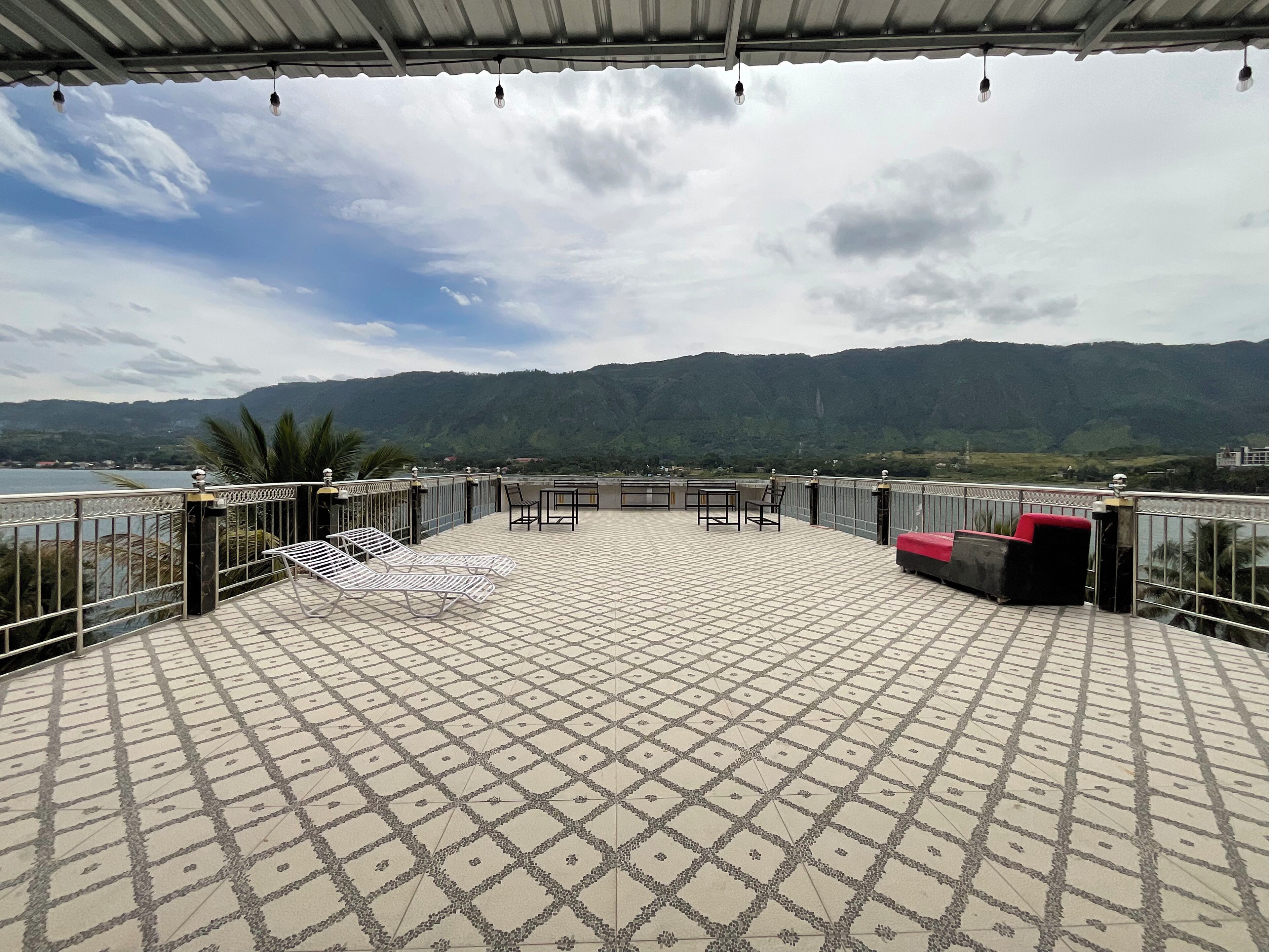 A terrace with a tiled floor, metal railing, and seating.