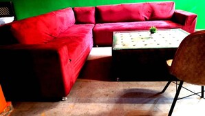 Un divano rosso, un tavolino con una pianta e una sedia in una stanza con una parete verde.