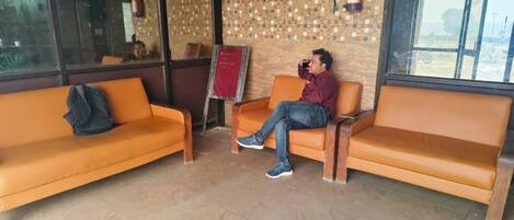 A seating area with orange couches and a fire extinguisher on the wall.