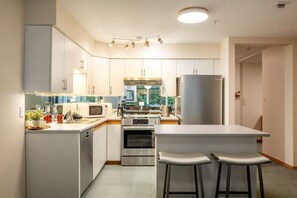 Eine moderne Küche mit weißen Schränken, Edelstahlgeräten und einer zentralen Kochinsel mit Barhocker.