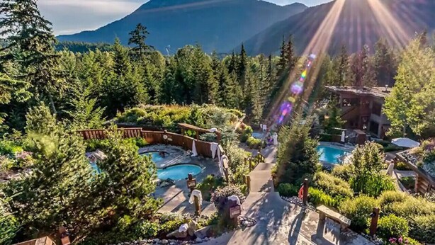 Ein Resort mit mehreren Schwimmbecken, umgeben von üppiger Vegetation und Bergen im Hintergrund.