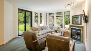 Ein modernes Wohnzimmer mit großem Fenster, Kamin und Flachbildfernseher.