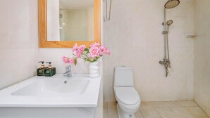 Un baño con un lavabo blanco, inodoro, ducha y espejo con marco de madera.