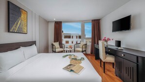 Habitación de hotel con cama, escritorio, televisor y vistas a edificios.