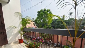 A balcony with potted plants and a view of parked motorcycles on the street. - Sri Inn (Puducherry)