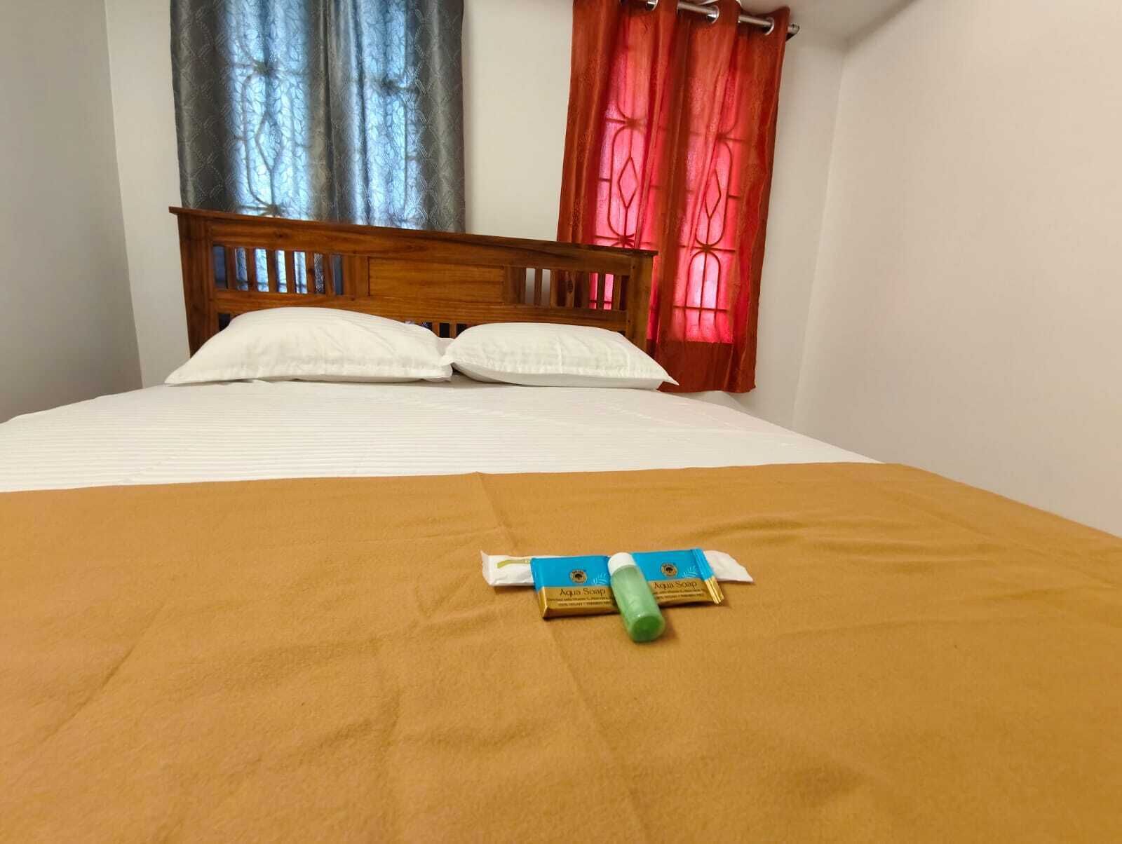 Una cama con una colcha marrón, dos almohadas blancas y un cabecero de madera.
