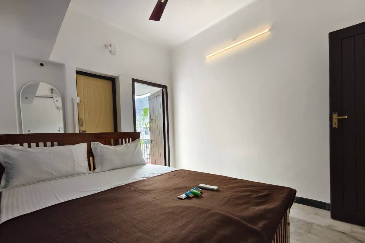 Une chambre d’hôtel avec un grand lit, une tête de lit en bois, un miroir et une porte donnant sur un balcon.