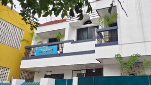 A multi-story building with a blue sign reading "Sriyan" on the ground floor. - Sri Inn (Puducherry)