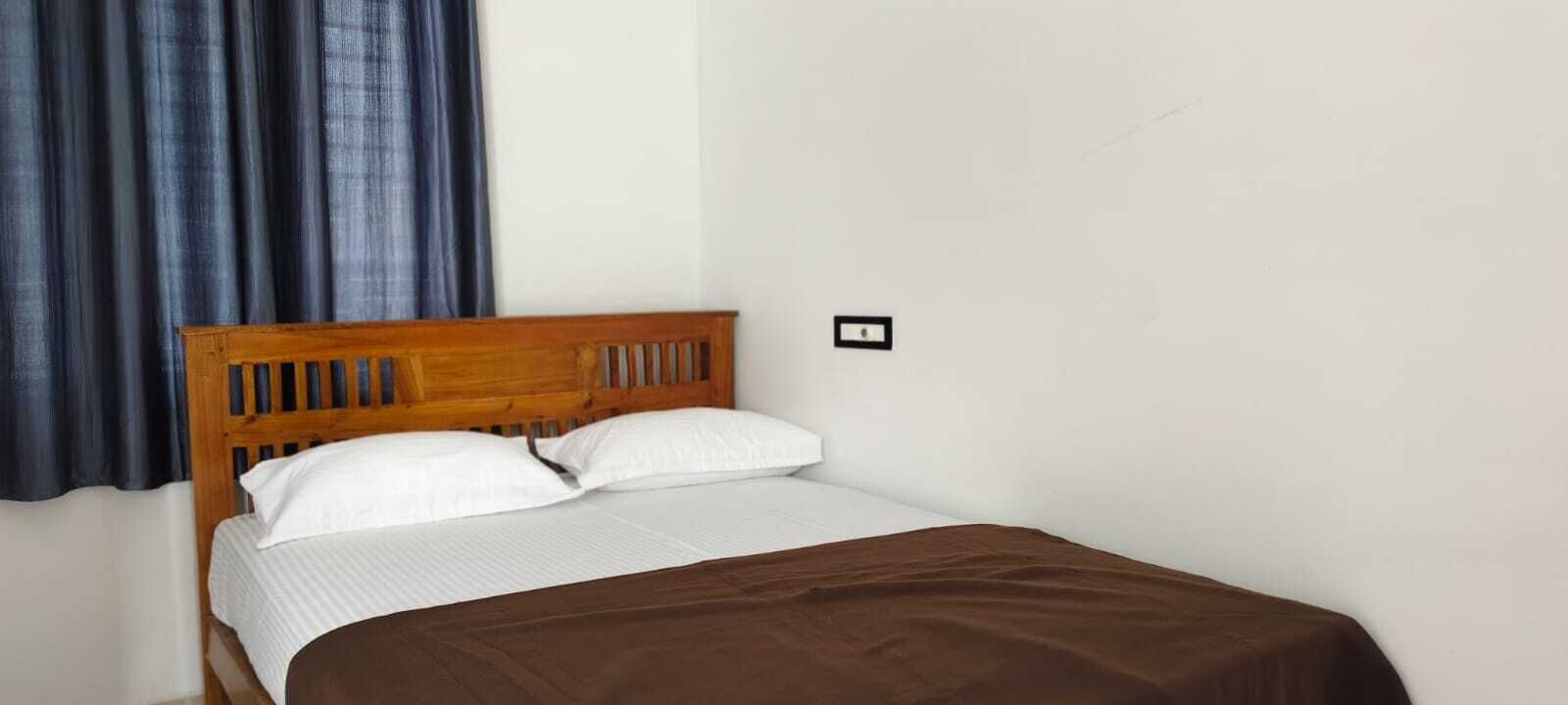 Ein Einzelbett mit Holz-Kopfteil, weißer Bettwäsche und einer braunen Decke.