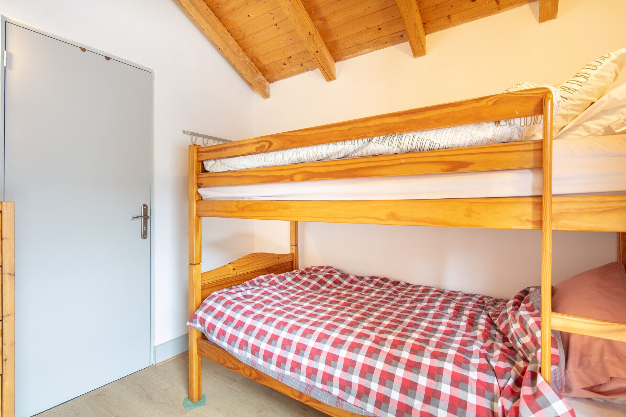 A bunk bed with a checkered bedspread and a wooden headboard.