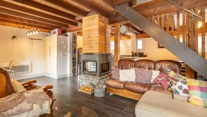 Una sala de estar acogedora con chimenea, vigas de madera, un sofá y una escalera.