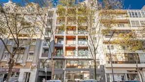 Un edificio residenziale a più piani con balconi, auto parcheggiate e un cartello di un ristorante ben visibile.